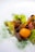 A gourmet dish featuring a vibrant yellow cherry tomato, surrounded by tender slices of cooked meat and lush green lettuce leaves. Garnished with dark berries and sprinkled finely with green herbs, adding a touch of elegance and freshness.