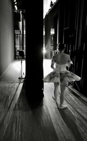 a woman in a ballet outfit is standing on a wooden floor