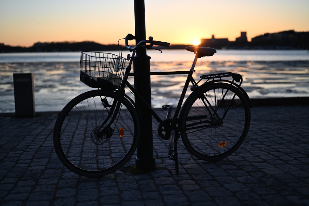 a bike parked next to a pole on a sidewalk