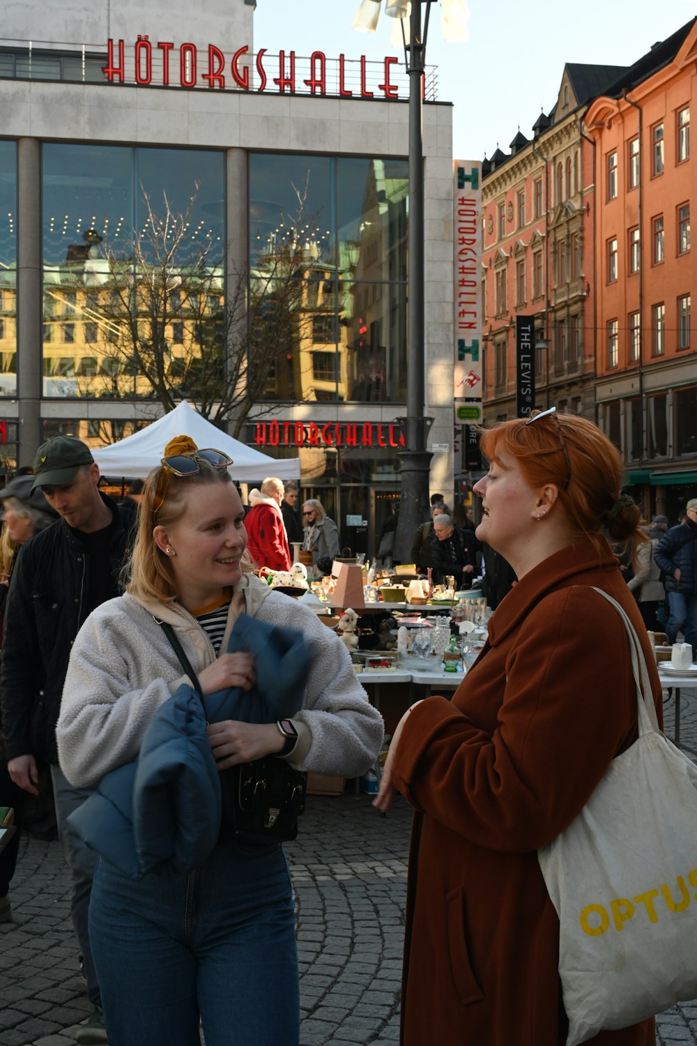 two women are talking in front of a store