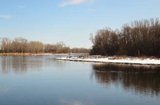 Helicopter hovering over a clear, shimmering river winding through the silent winter landscape.