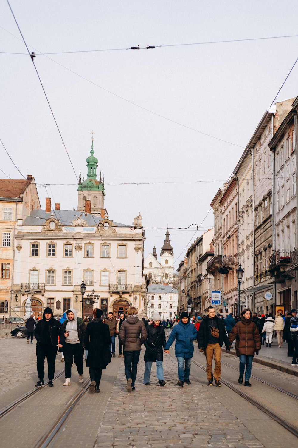 a group of people walking down a street next to tall buildings