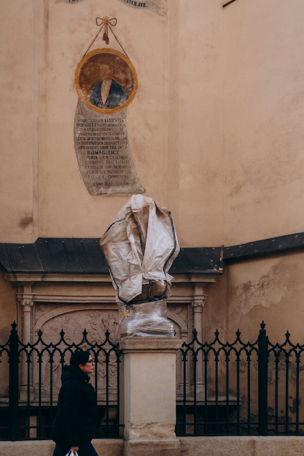 a woman walking past a statue in front of a building