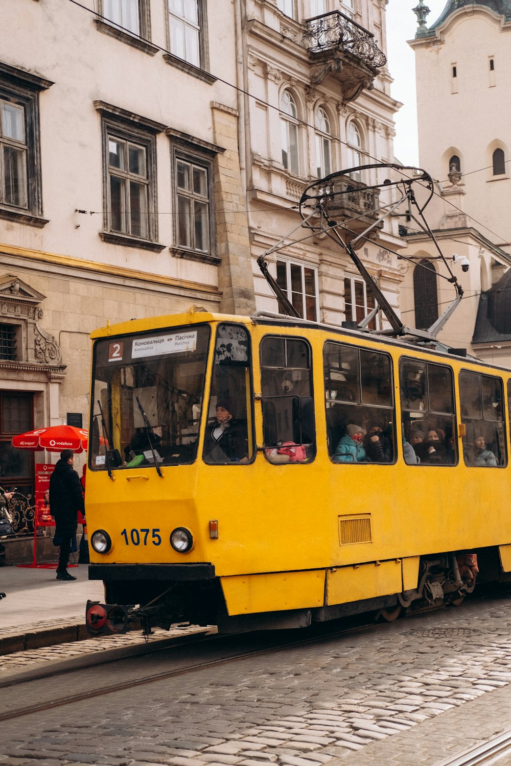 Eine gelbe Straßenbahn fährt eine Straße neben hohen Gebäuden entlang