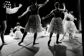 An elegant snapshot of a ballet troupe gracefully posing on a dimly lit theater stage.