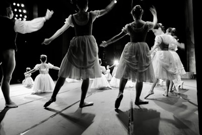 An elegant snapshot of a ballet troupe gracefully posing on a dimly lit theater stage.