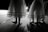 Dancers in delicate, layered skirts standing on a dimly lit stage, casting soft shadows on the floor.