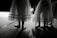 Dancers in delicate, layered skirts standing on a dimly lit stage, casting soft shadows on the floor.