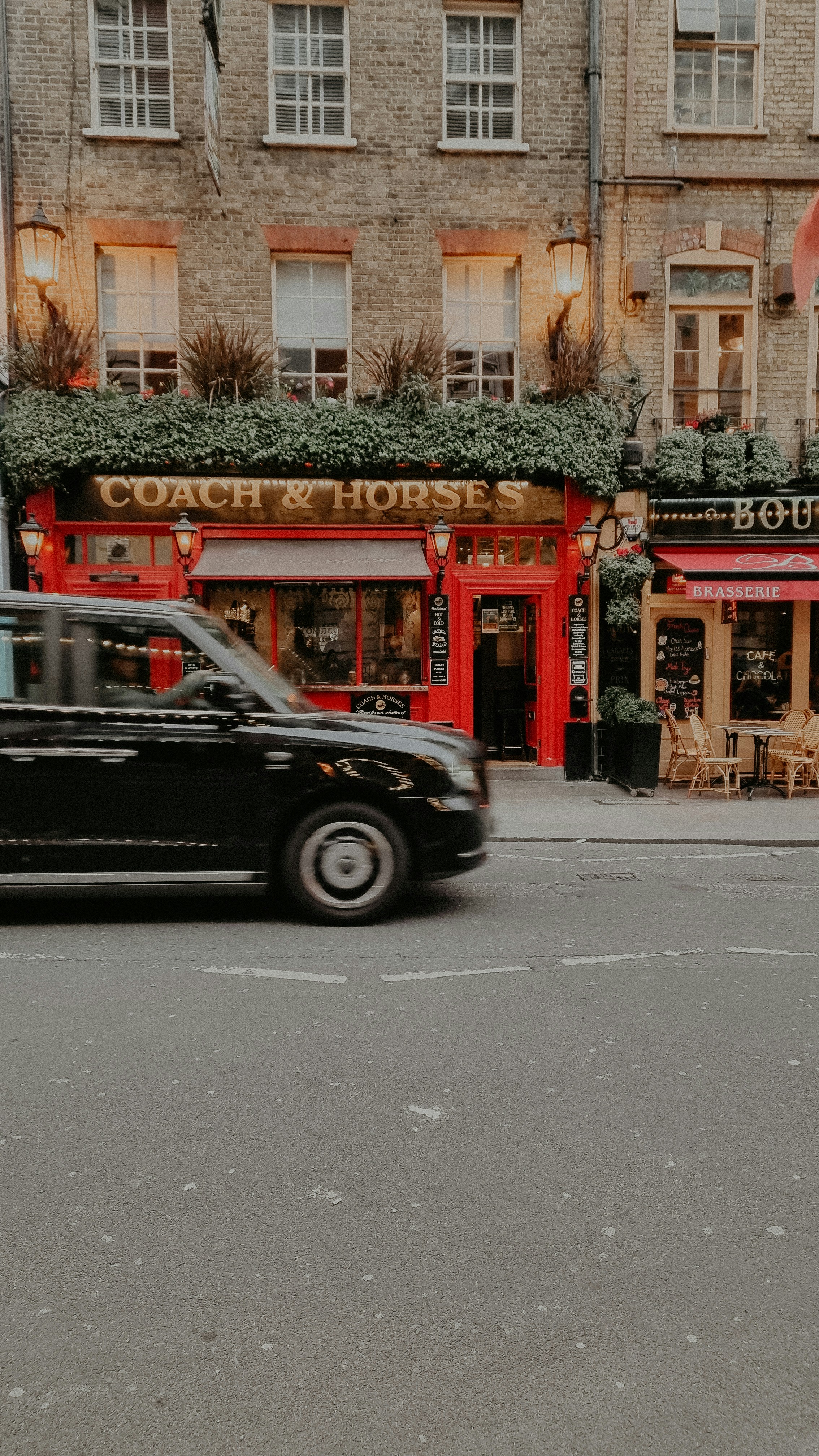 Ein schwarzes Auto, das eine Straße neben hohen Gebäuden hinunterfährt