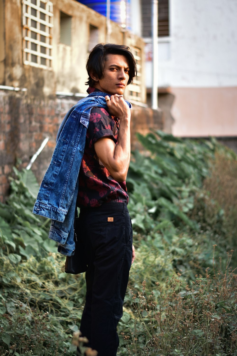 a man standing in a field with a jacket on his shoulders