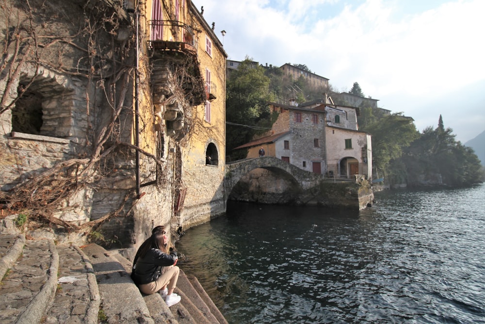 a person sitting on a ledge next to a body of water