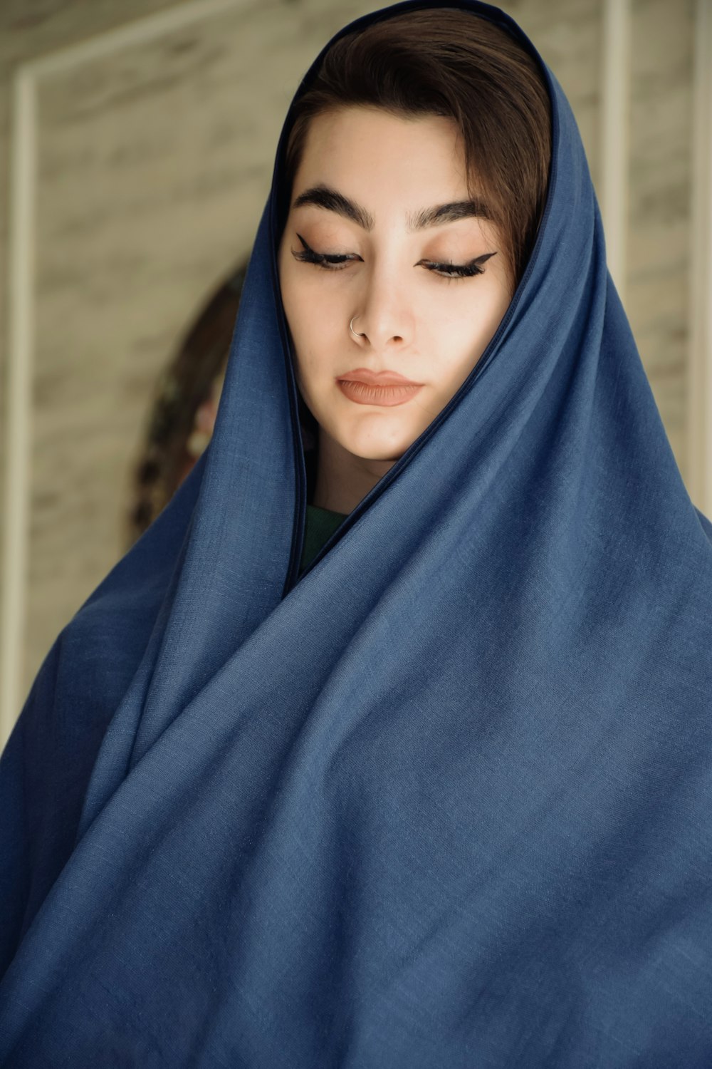 a woman wearing a blue shawl with her eyes closed