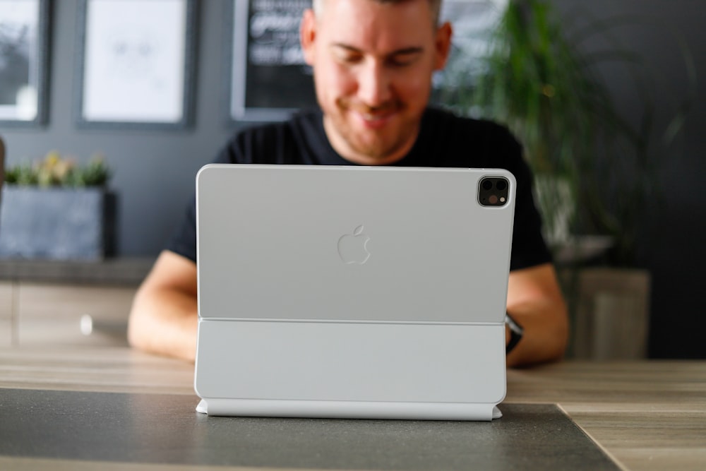 a man sitting at a table looking at a laptop