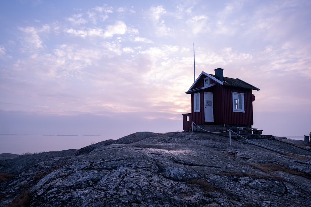 a small red house sitting on top of a rocky hill