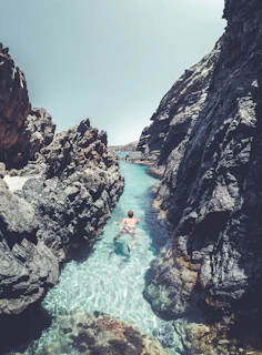 Swimmer cutting through turquoise ocean water near El Arco at sunrise.