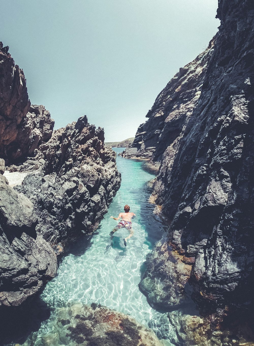 uma pessoa nadando em um corpo de água cercado por rochas