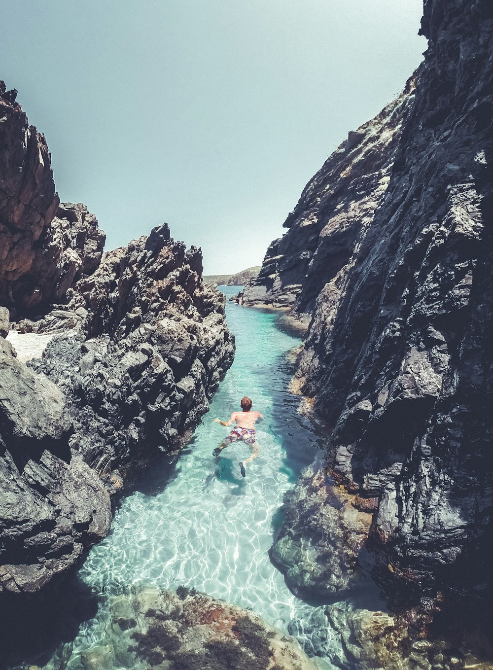 a person swimming in a body of water surrounded by rocks