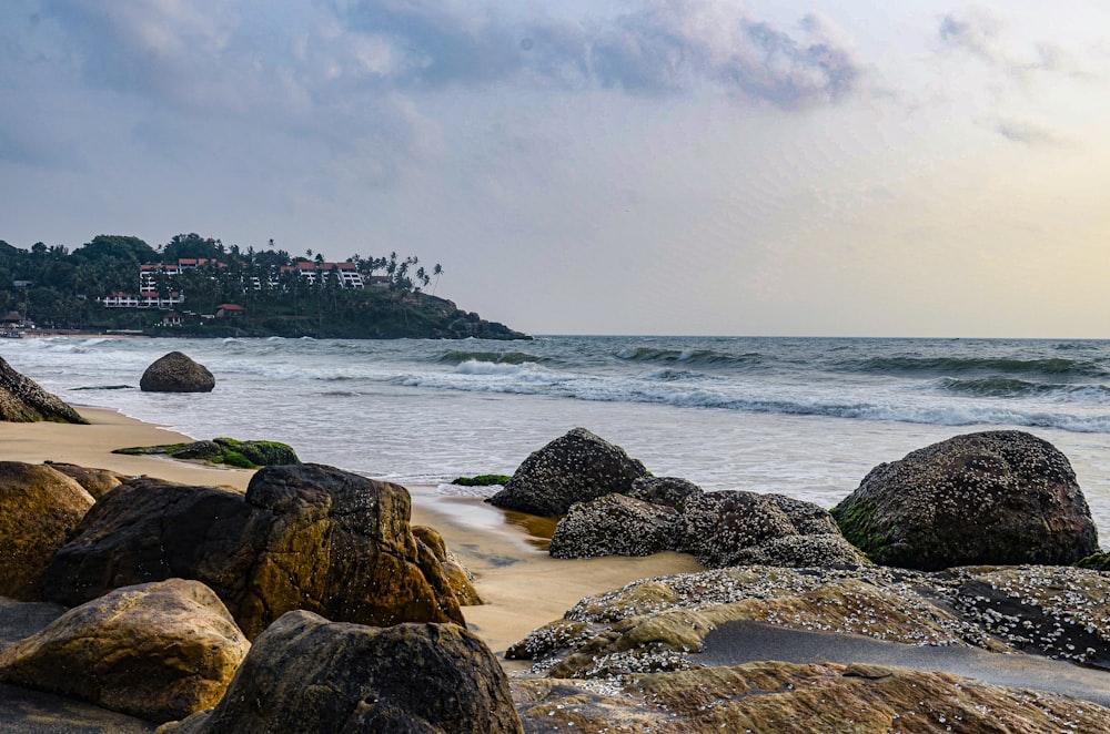 a sandy beach with large rocks in the foreground