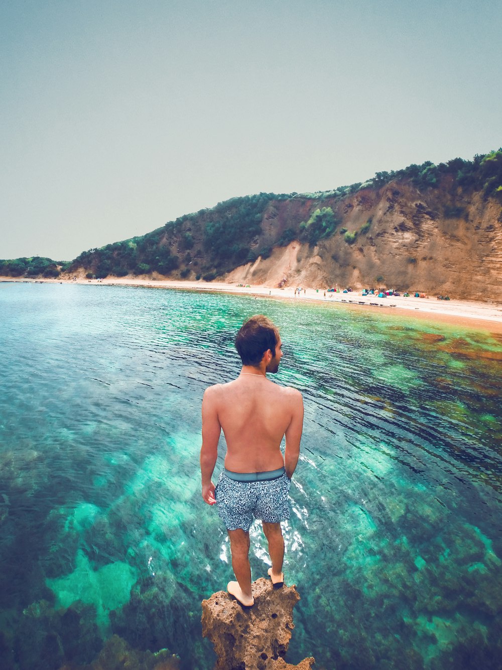 Un uomo in piedi su una roccia che guarda l'oceano