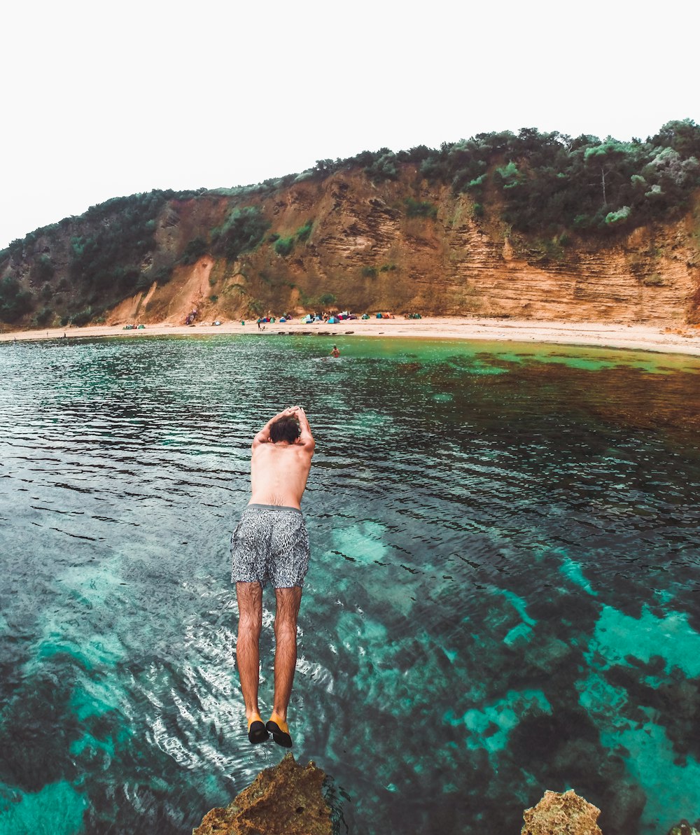 a man standing on a rock in the middle of a body of water