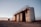 A group of large, cylindrical storage tanks is located on a barren, gravel-covered landscape. The tanks are connected by a metal catwalk with stairs leading to the top. The sky in the background is clear with subtle hues of a sunset or sunrise, casting a soft pink and orange glow.