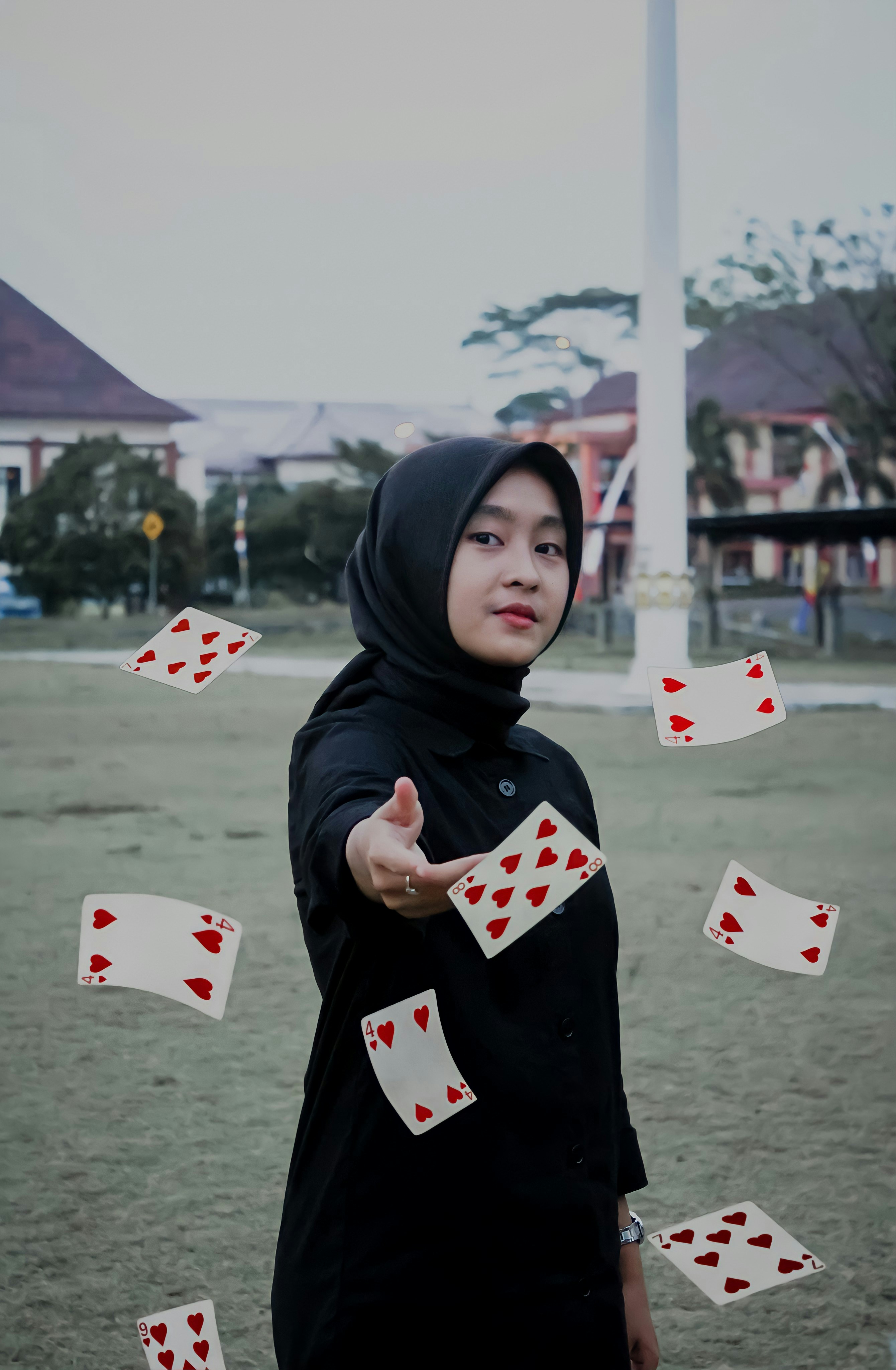 a woman in a hoodie throwing playing cards in the air
