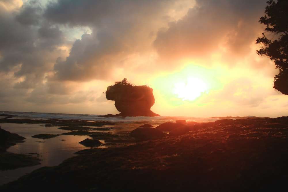 the sun is setting over a rocky beach