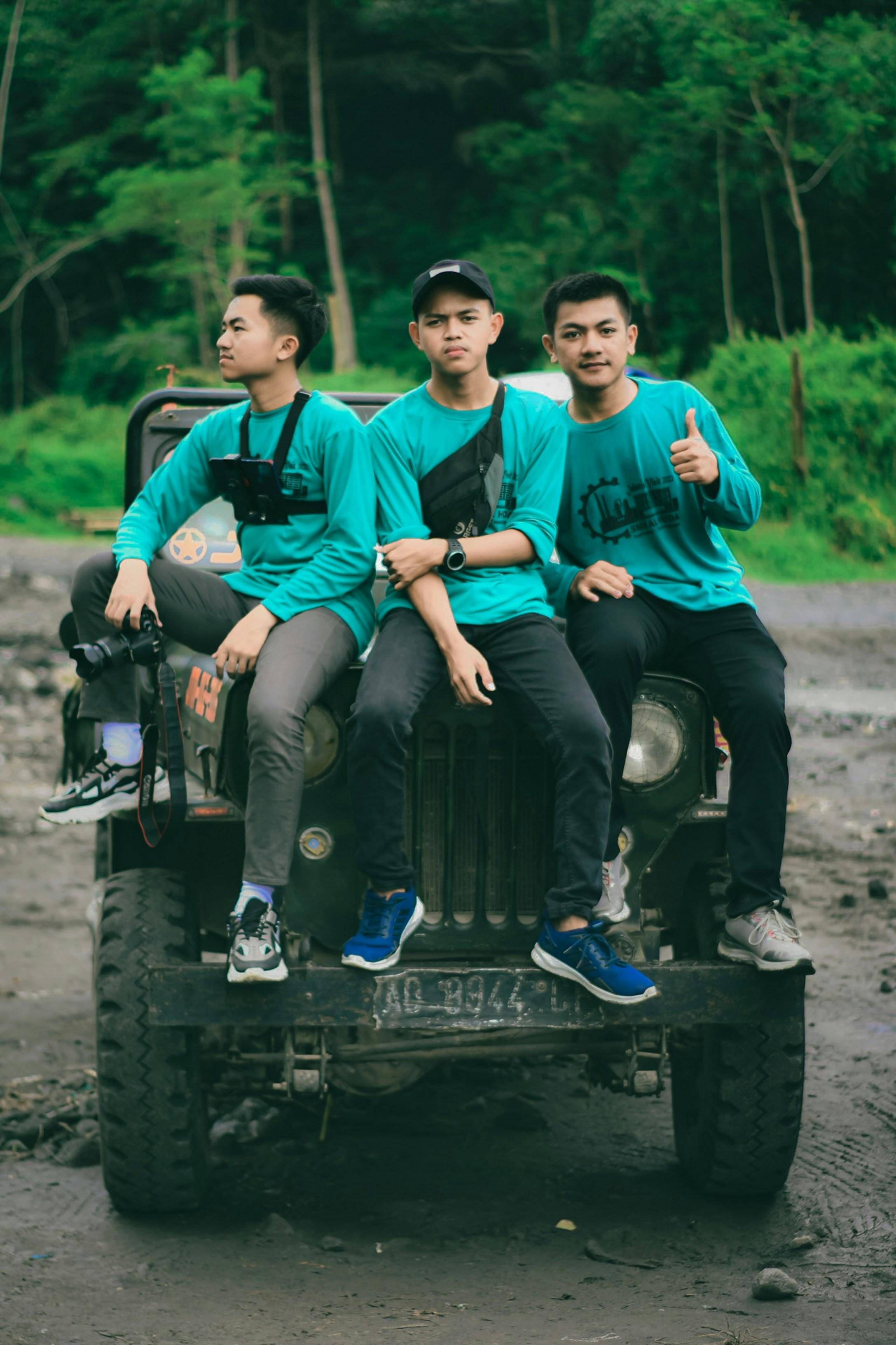 three young men sitting on the back of a jeep