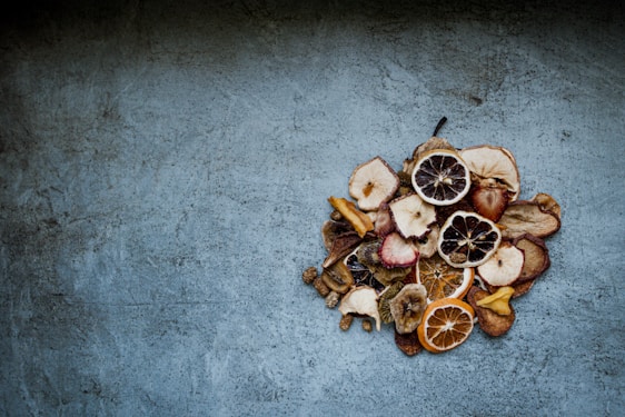 Close-up of vibrant dried fruit slices arranged on rustic wooden table with natural light.