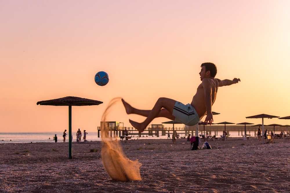 a man is playing with a ball on the beach