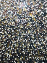 A large number of wine bottles are scattered randomly across the surface, creating a chaotic and colorful pattern. The bottles vary in color, indicating different wine varieties such as red, white, and rosé.