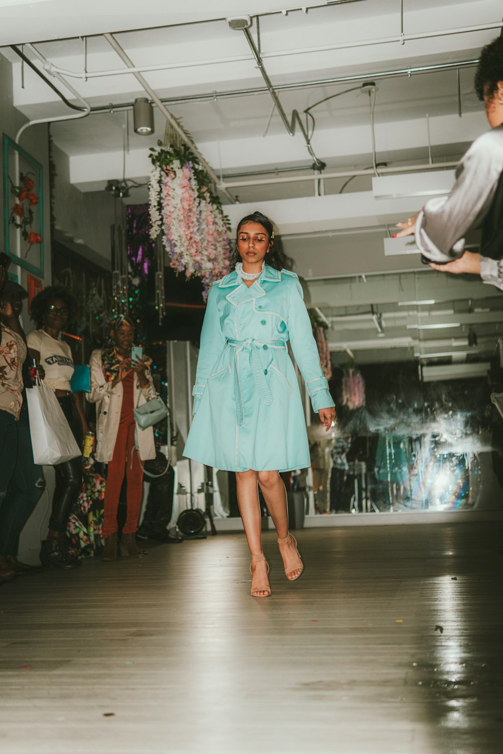 a woman in a blue coat walking down a runway