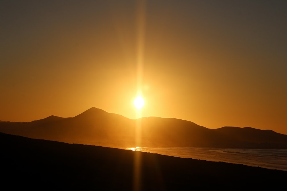 the sun is setting over a mountain range