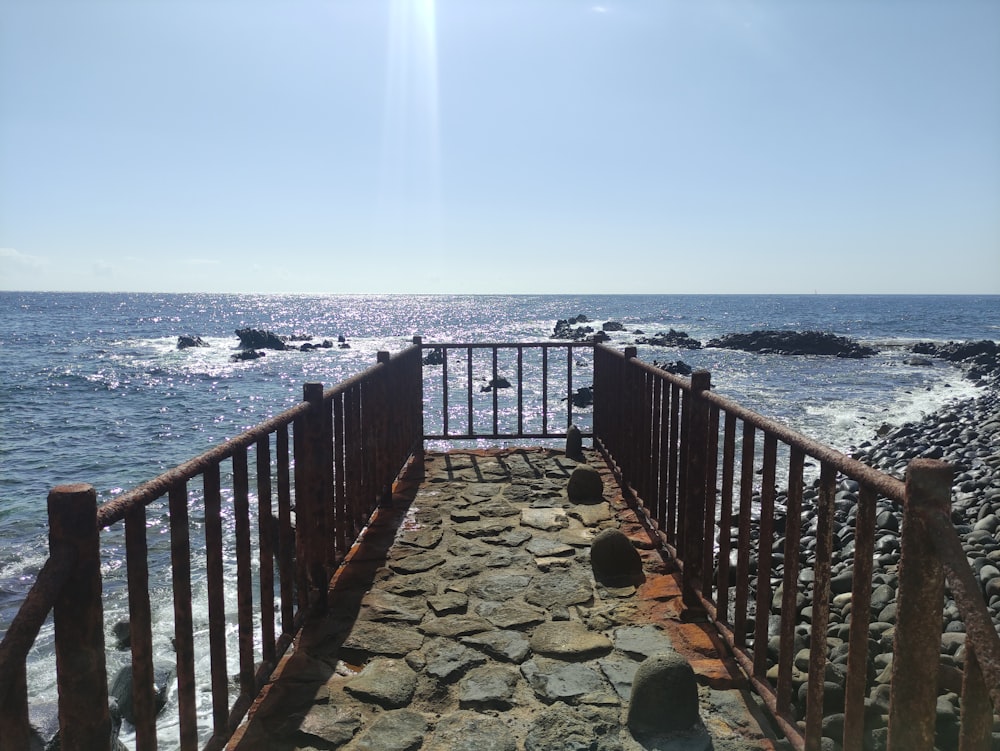 a stone walkway leading to the ocean on a sunny day