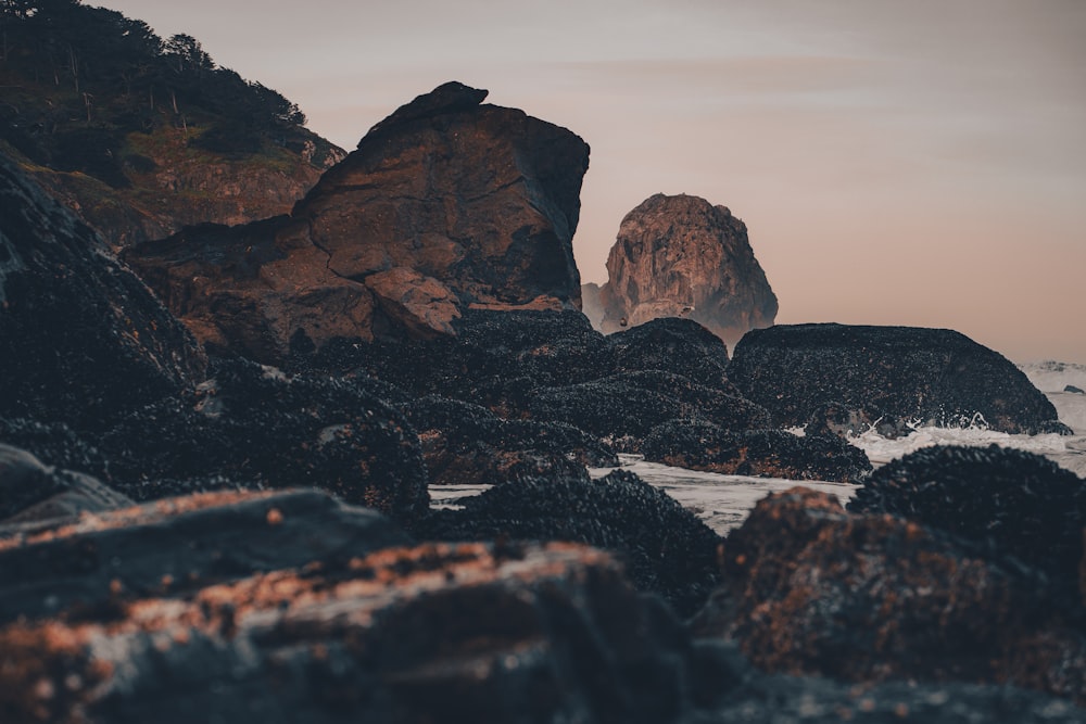 a rocky beach with a rock formation in the background