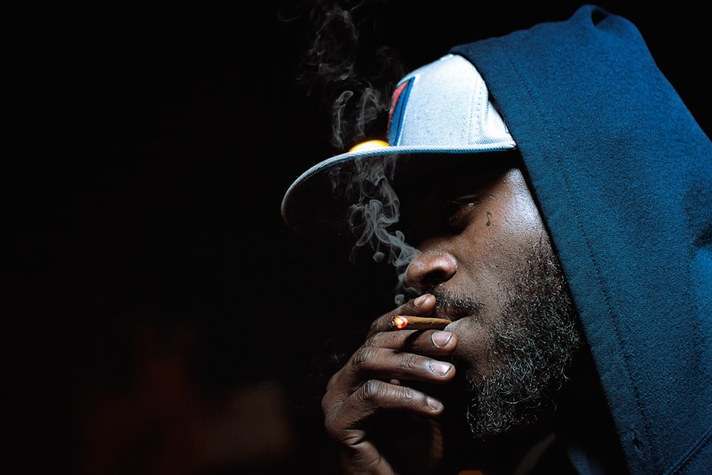 a man with a hat on smoking a cigarette