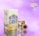 A saffron packaging design featuring a large rectangular box and a smaller round container. The background is a soft gradient of pinks and purples. The packaging is adorned with floral imagery and intricate geometric patterns in shades of blue and gold. The brand name 'ATIGH SAFFRON' is prominently displayed along with a decorative logo.