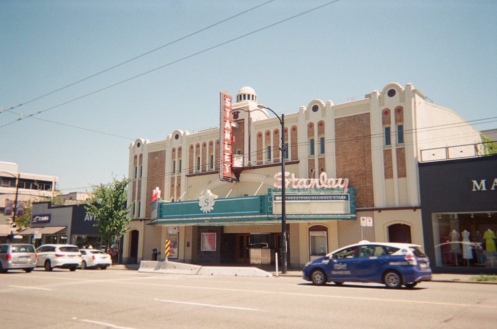 a blue car parked in front of a movie theater