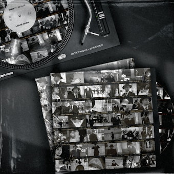 A vintage-style image features a vinyl record player with a record labeled 'Ricky Rique - Love Gun' on the turntable. Nearby, there are film contact sheets displaying black-and-white images of people, including individuals in suits and hats, evoking a classic or retro feel.