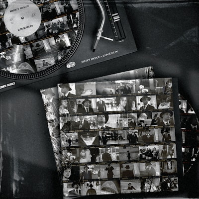 A vintage-style image features a vinyl record player with a record labeled 'Ricky Rique - Love Gun' on the turntable. Nearby, there are film contact sheets displaying black-and-white images of people, including individuals in suits and hats, evoking a classic or retro feel.