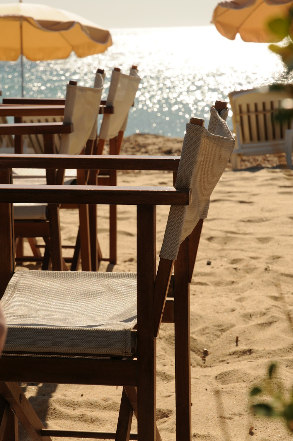 a row of wooden chairs sitting on top of a sandy beach