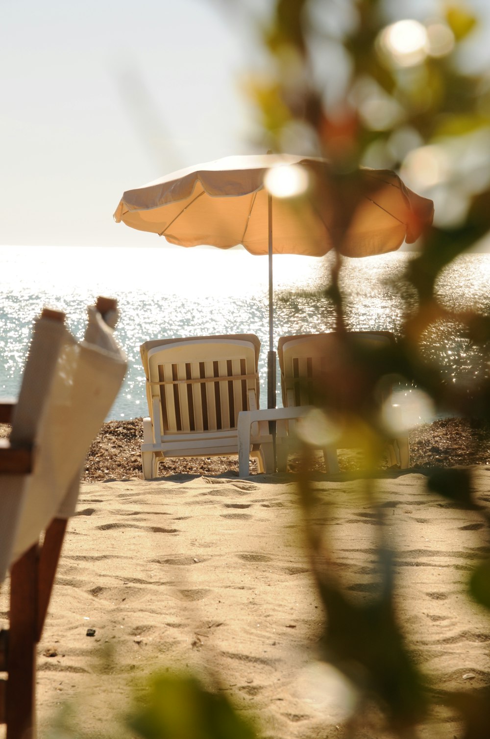um par de cadeiras de gramado sentadas em cima de uma praia de areia