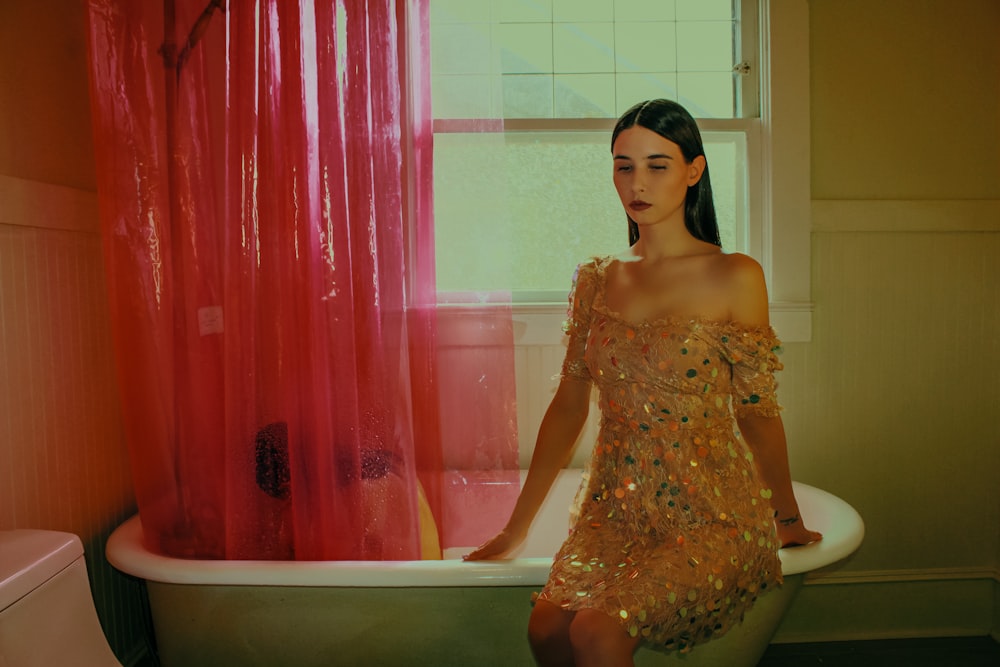 a woman sitting in a bathtub next to a red curtain