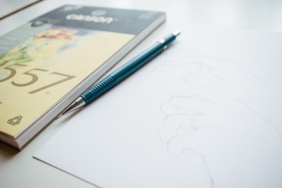 Close-up of hands sketching on a drawing pad with pencils.