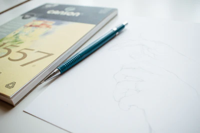 A close-up of hands sketching a vibrant life scene in a notebook, surrounded by colorful pencils and soft natural light.