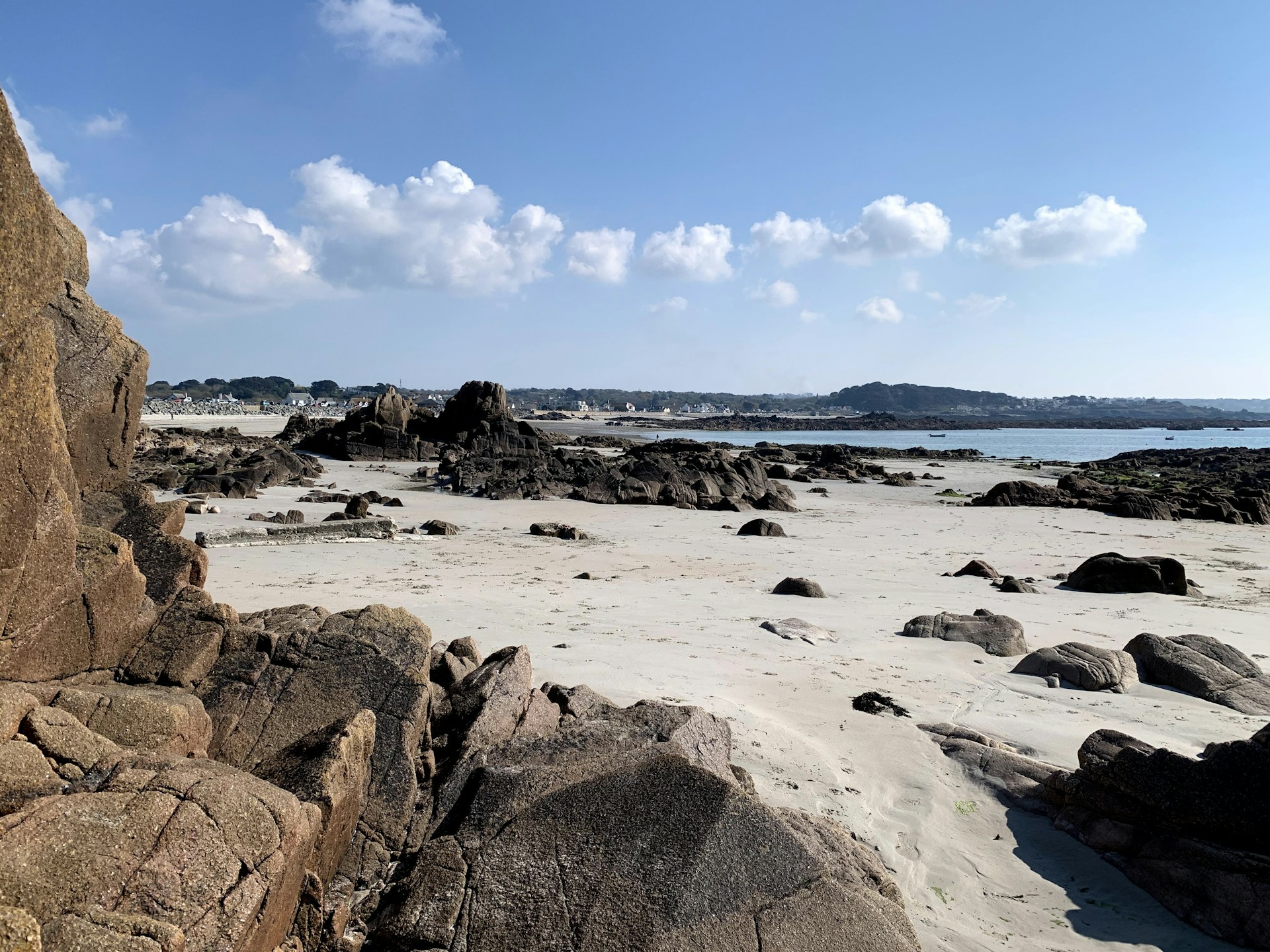 a sandy beach with rocks and water in the background