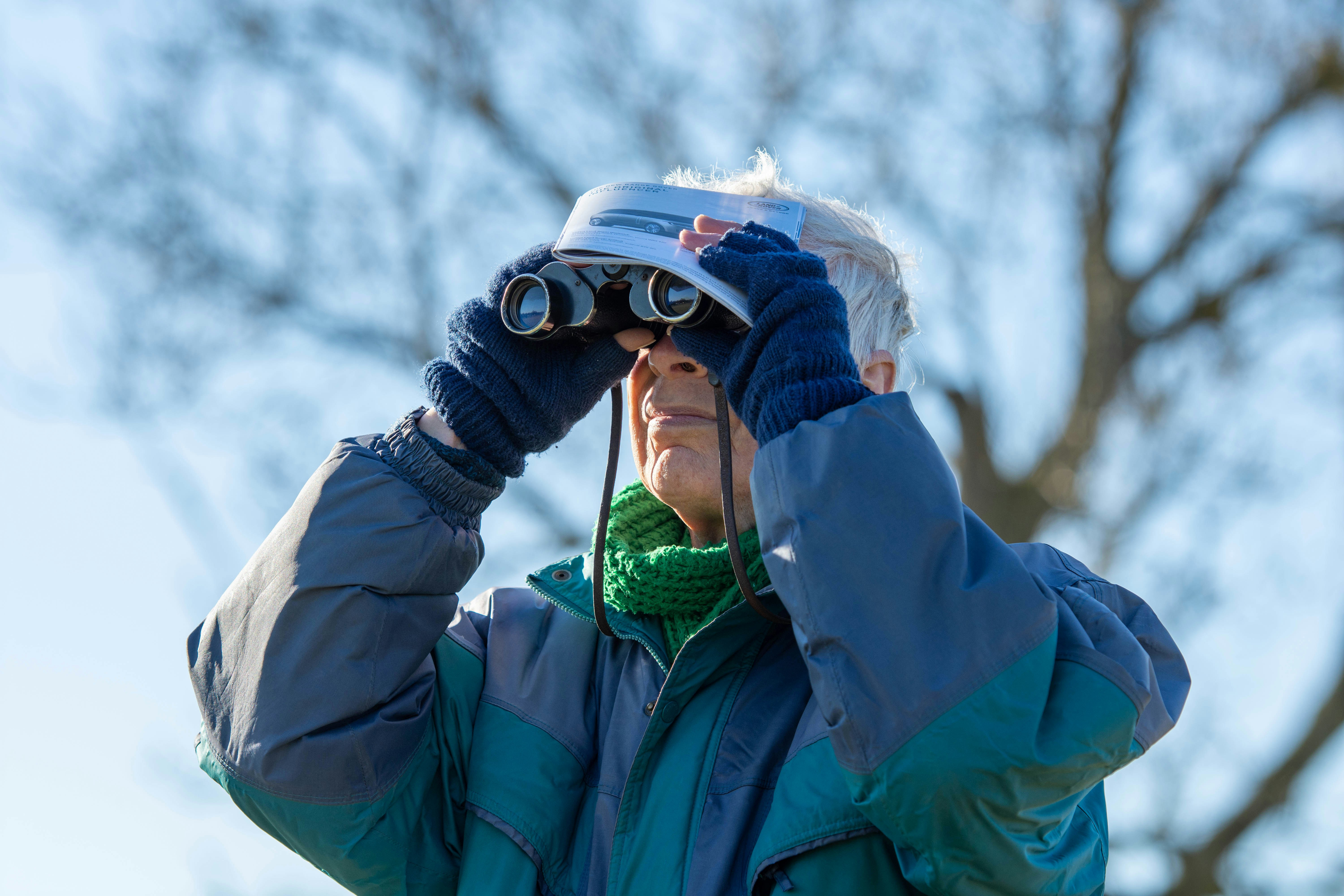 a man in a blue jacket looking through a pair of binoculars