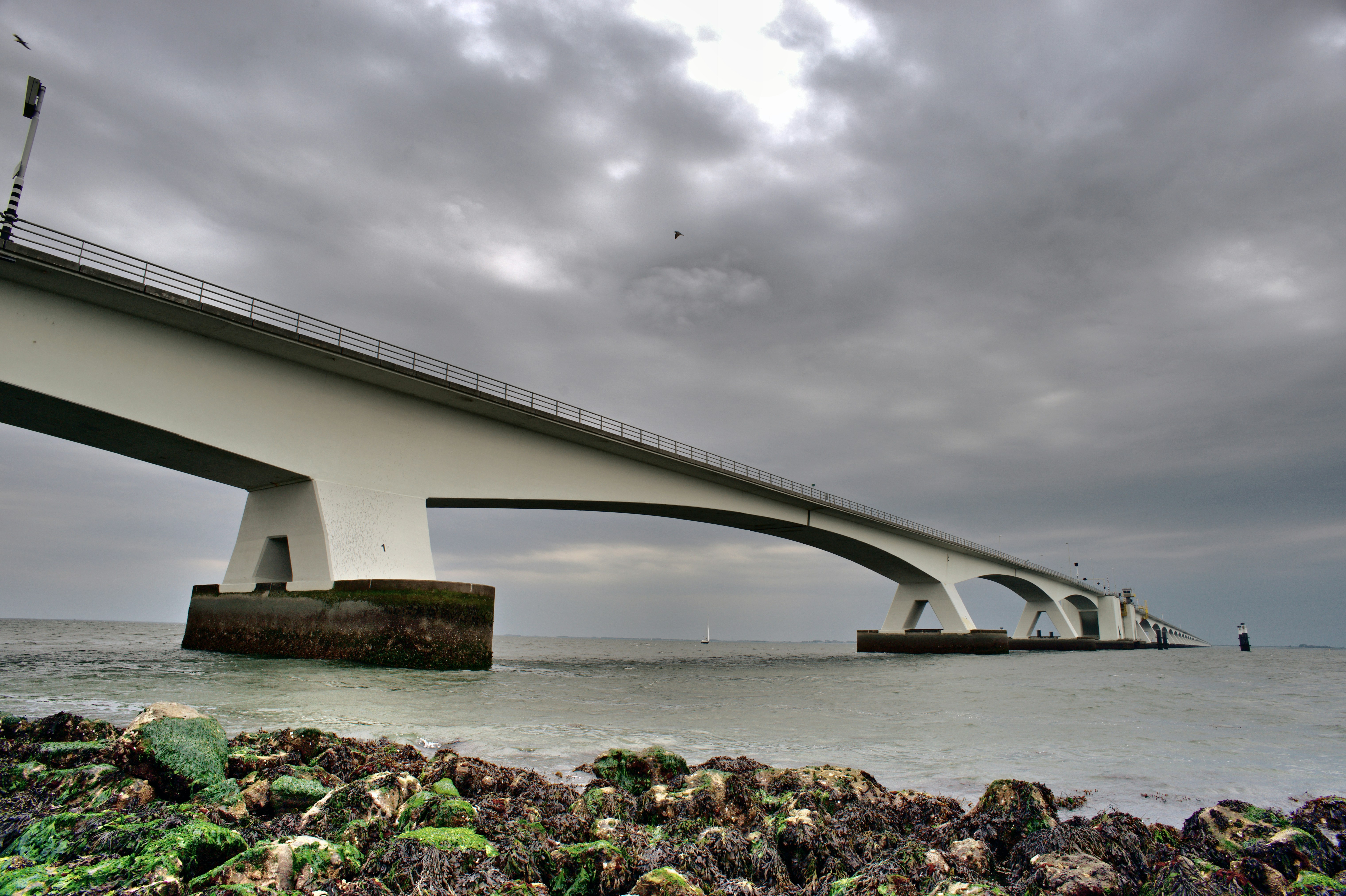 a bridge over a body of water under a cloudy sky