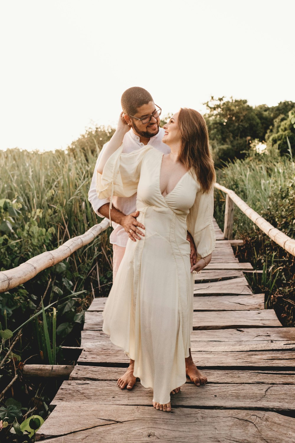 a man and woman standing on a wooden bridge