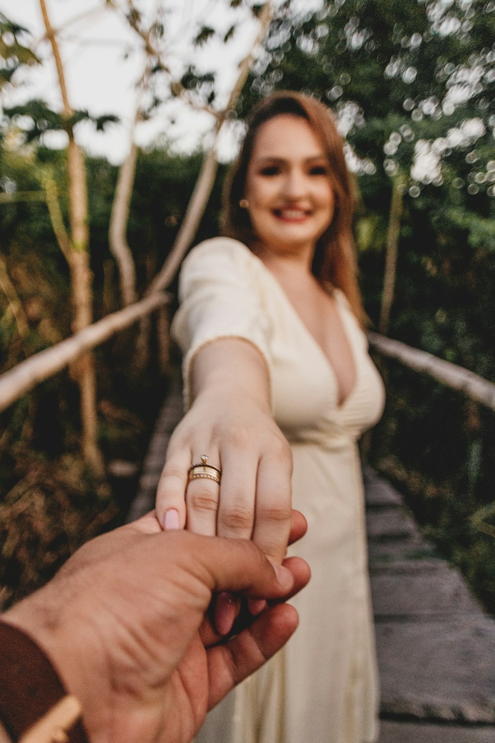 a woman holding the hand of a man on a bridge